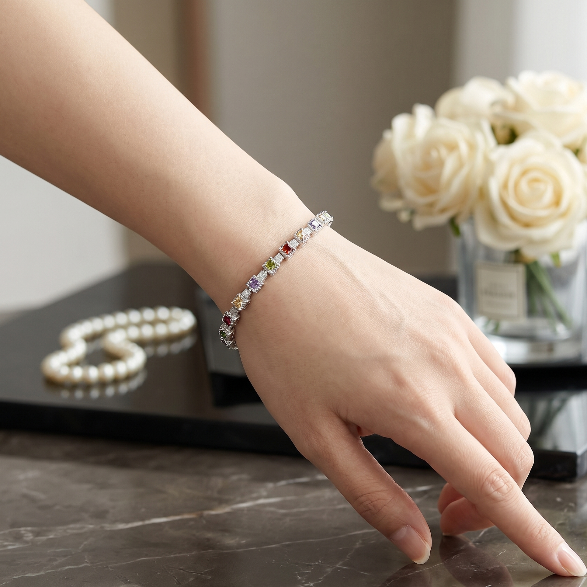 Hand wearing a bracelet with a blurred background of flowers and pearls